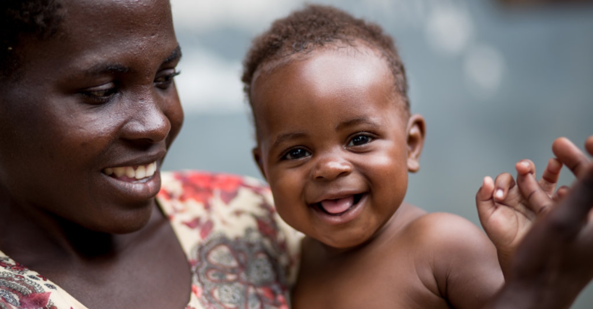 一位妇女抱着一个微笑的婴儿，婴儿直视前方