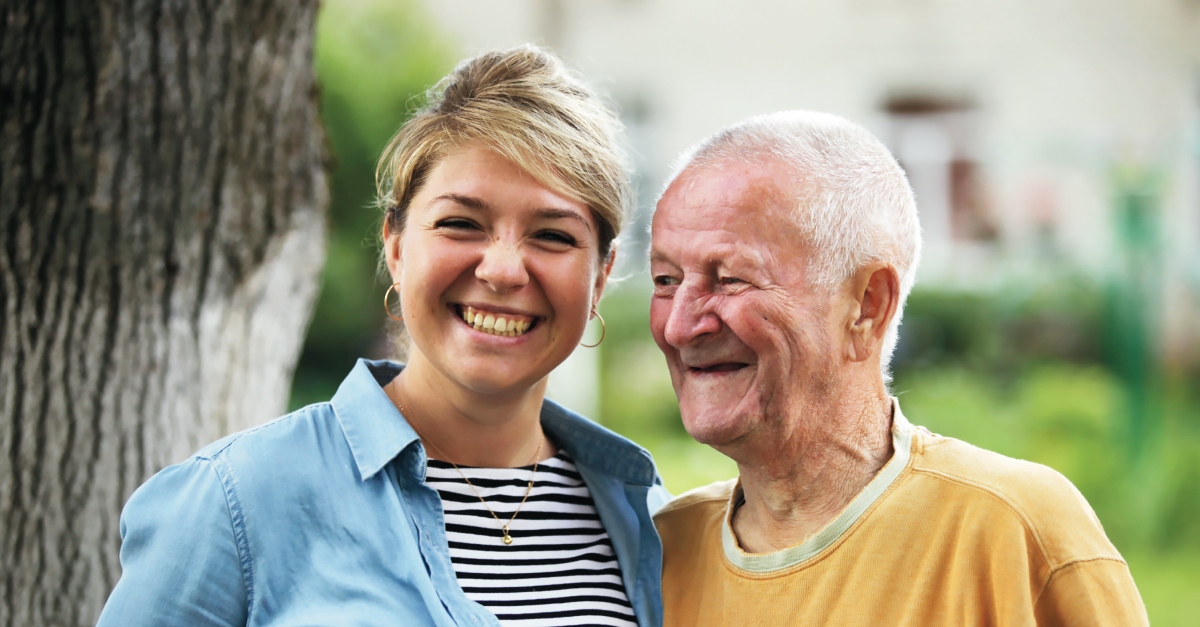 一个女人在一个黑色和白色的条纹衬衫,她微笑拥抱一位老人在一个黄色的衬衫。创造性的父亲节礼物