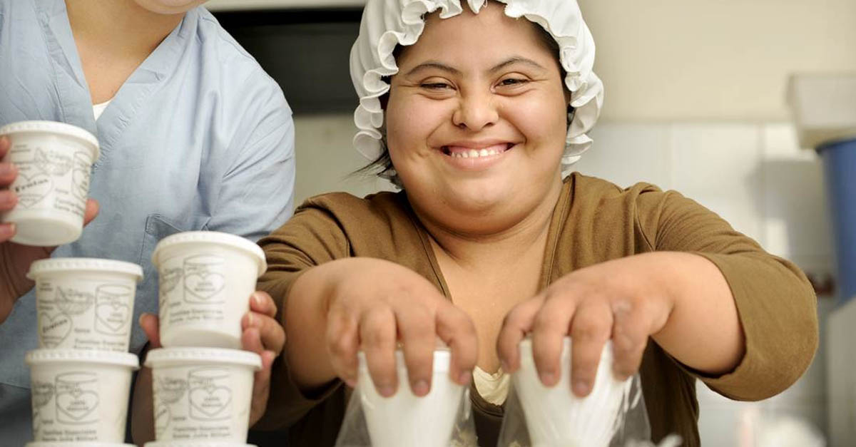 作为残疾儿童创新教育项目的一部分，一名女子手持新鲜酸奶容器