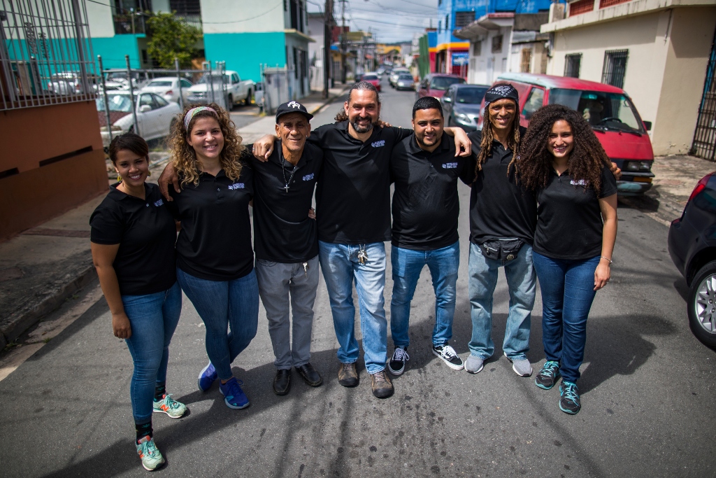 在波多黎各的街道上，一群人穿着相配的黑衬衫，手挽着手站在一起。