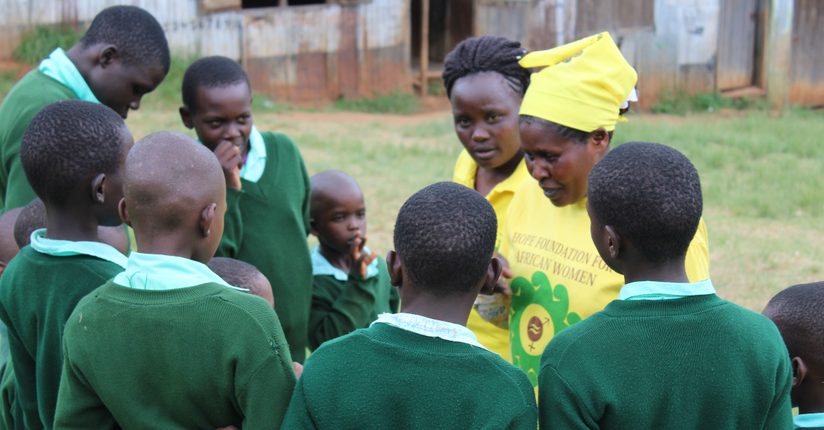 两名身穿黄色衬衫的妇女与一群身穿绿色制服的学生谈论关于女性生殖器切割的问题