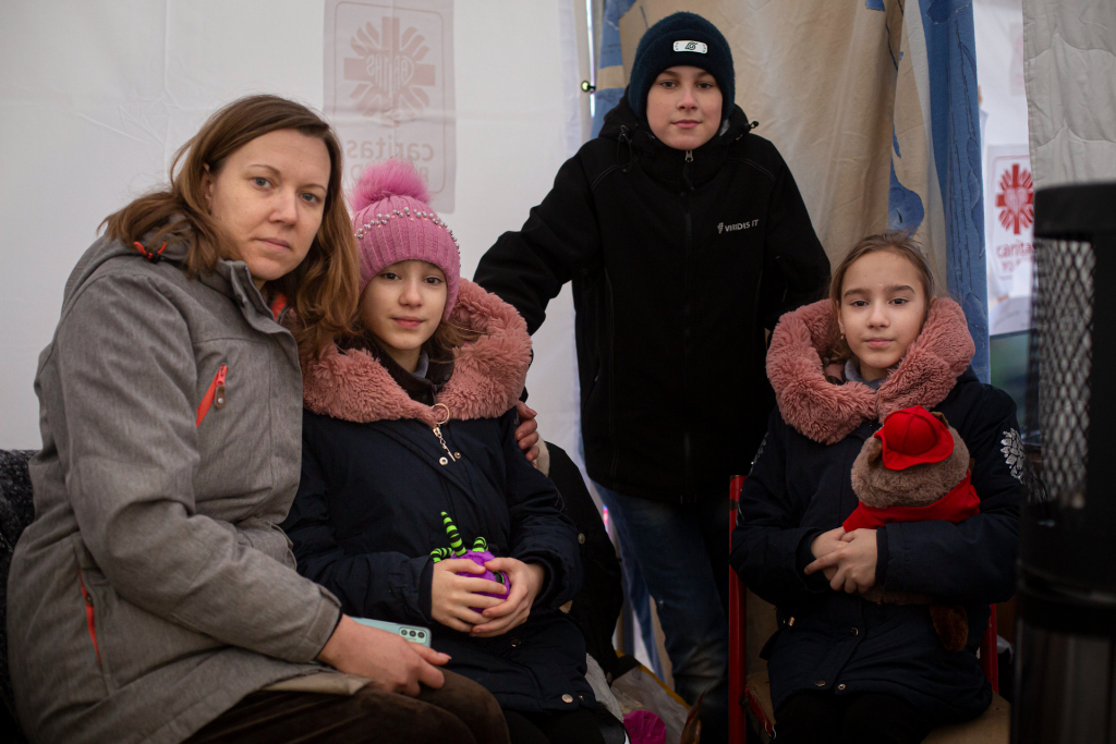 一名妇女和她的三个孩子坐在难民帐篷里。三人都穿着冬季夹克。卡塔尔世界杯预测非营利组织帮助乌克兰。