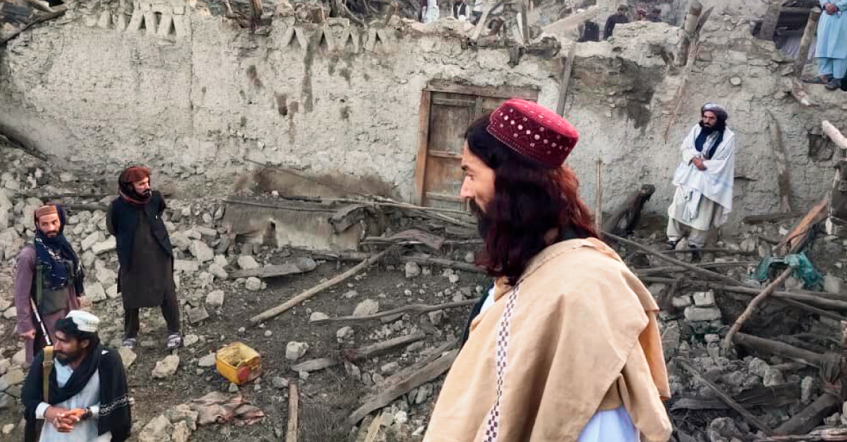 一名身穿棕褐色衣服的男子看着阿富汗地震中倒塌的建筑物