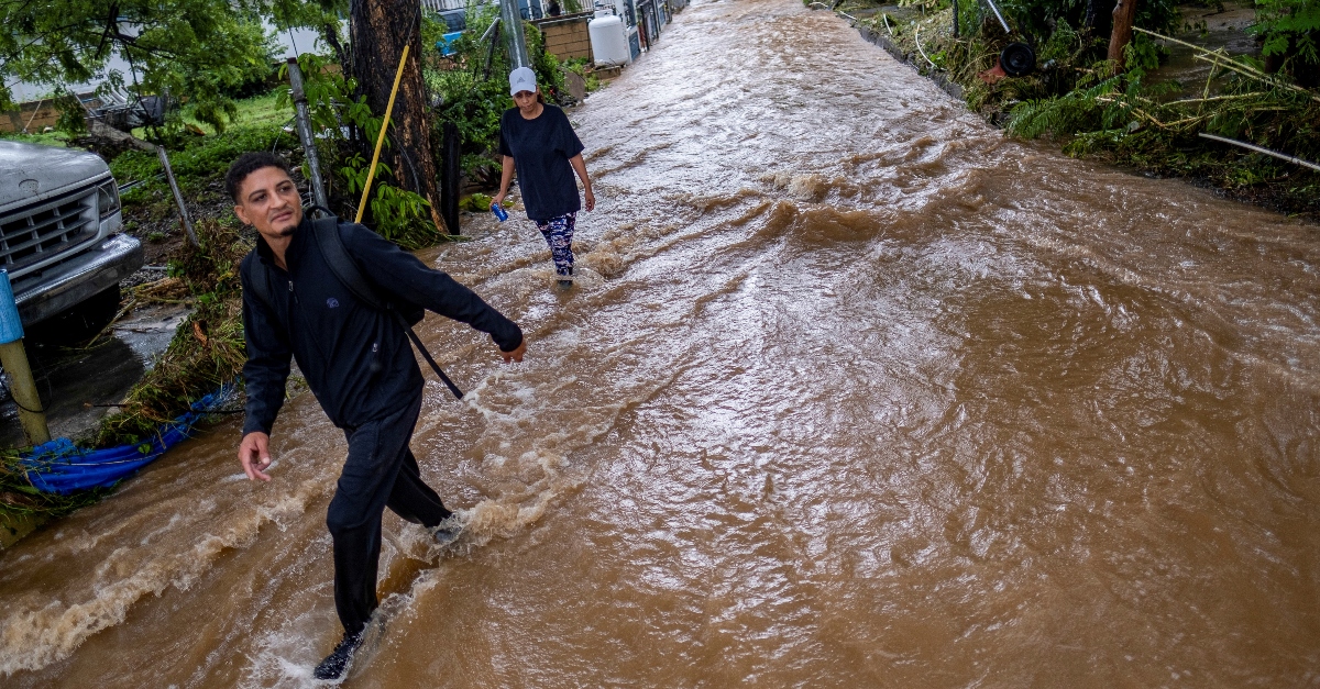 波多黎各萨利纳斯，菲奥娜飓风过后，两个人在被洪水淹没的街道上趟过棕色的水