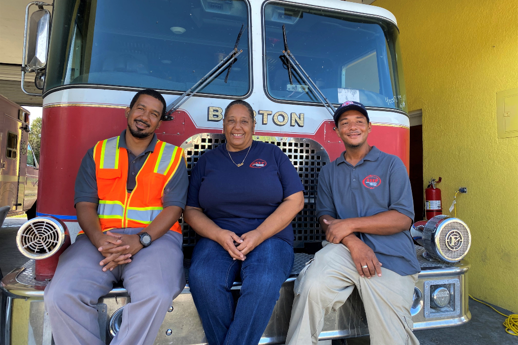 飓风多里安过后，三名工人坐在消防车的保险杠上