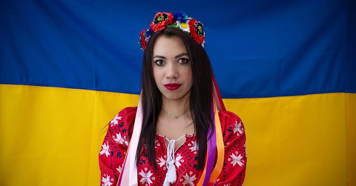 身着乌克兰传统服饰的妇女站在乌克兰国旗前。打网球是为了和平