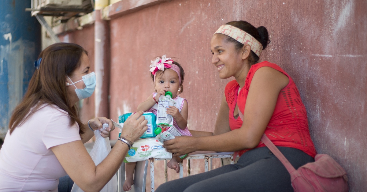 一名妇女和她年幼的女儿从委内瑞拉儿童之友工作人员那里接受儿童援助物资