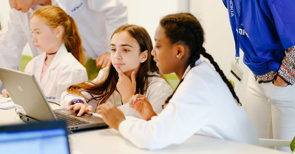 表情若有所思的女孩们围坐在笔记本电脑旁学习编程。一个来自世界各地的性别平等倡议的例子，在新的一年里强调。