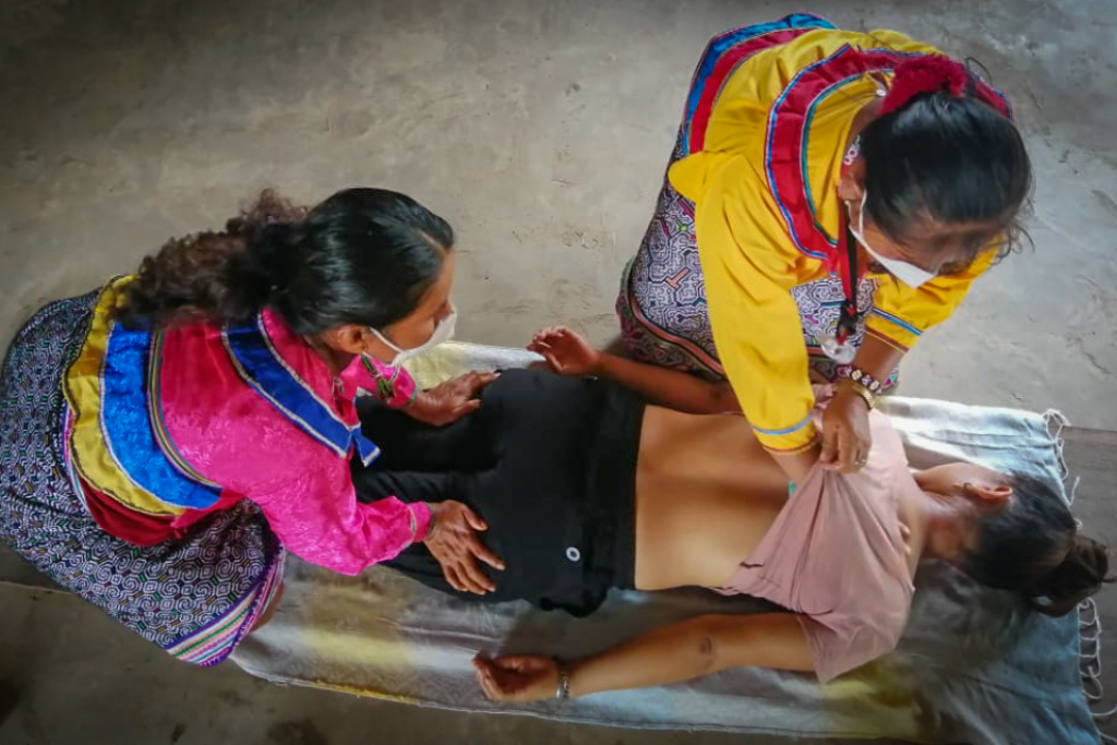 两名妇女进行治疗按摩，另一名妇女躺在她的腹部。