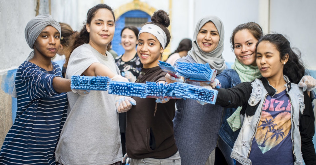 女孩们拿着涂着蓝色颜料的画笔微笑着。避免资助仇恨和极端主义。