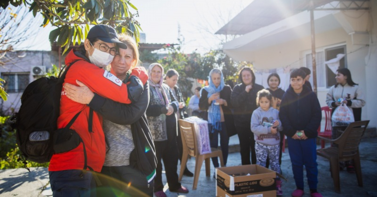 家人站在后面，妇女拥抱向土耳其和叙利亚地震捐款的救援人员