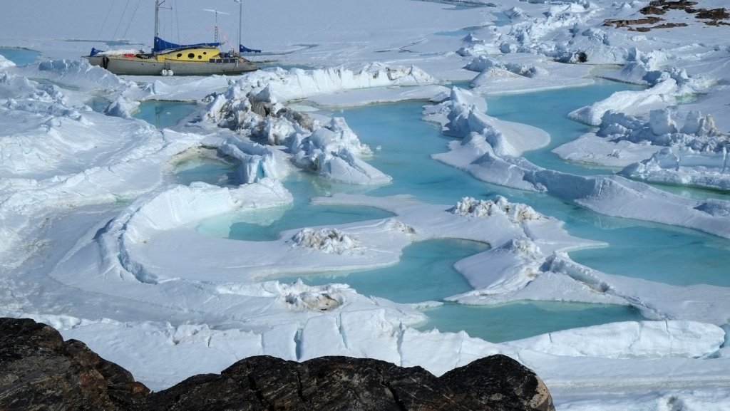 在结冰的湖面或海洋上的一艘船，靠近一些蓝色的水潭